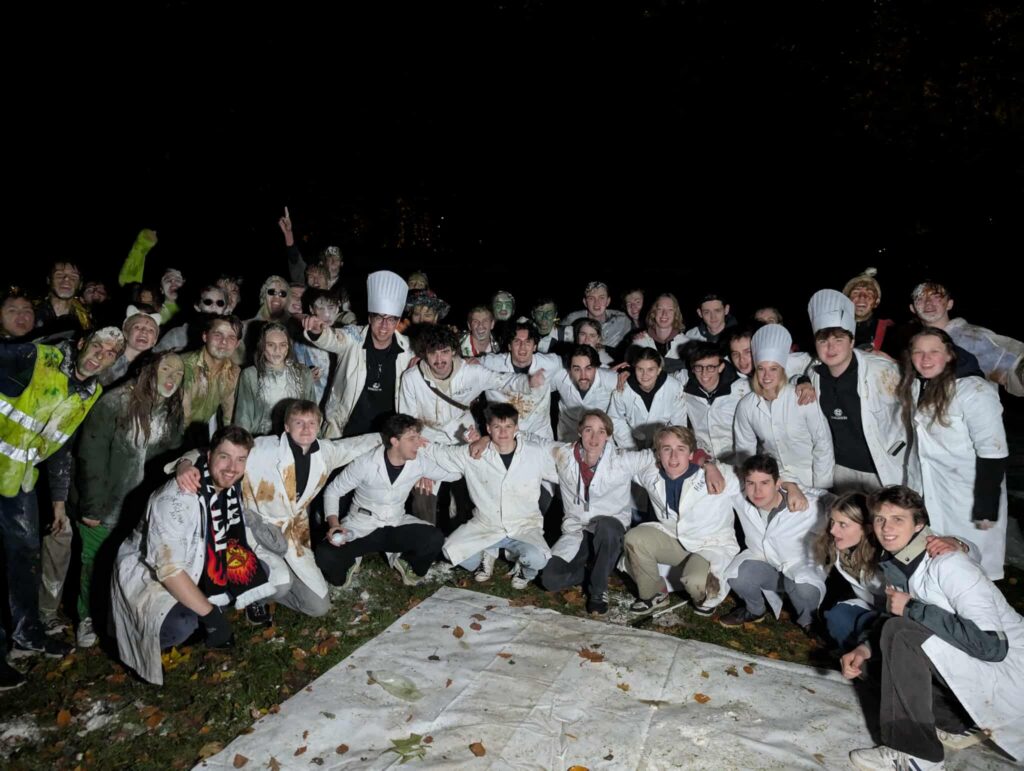 Groepsfoto van de gedoopten en doopmeesters in witte labojassen na de doop